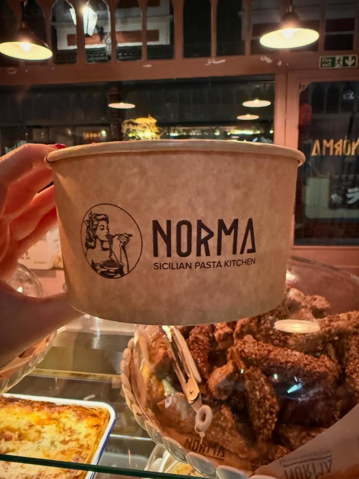 A Norma branded takeaway bowl held inside the restaurant