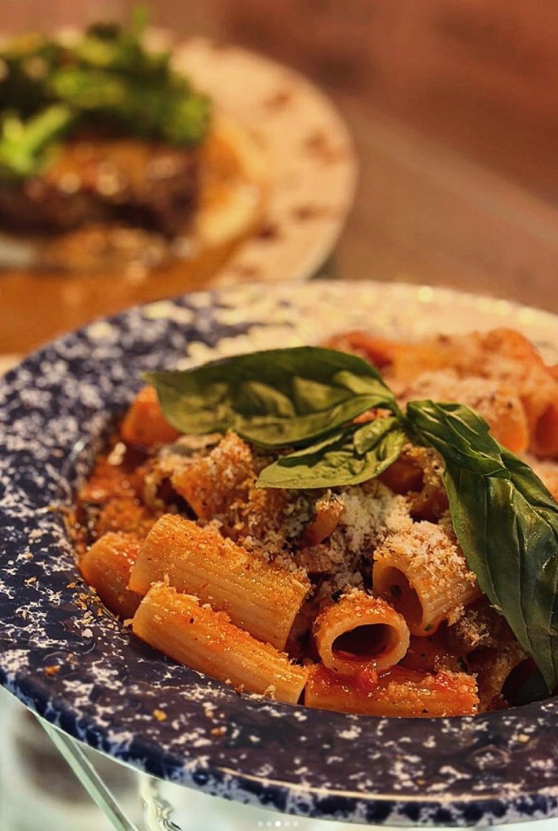 A bowl of Norma rigatoni with tomato, basil and grated cheese